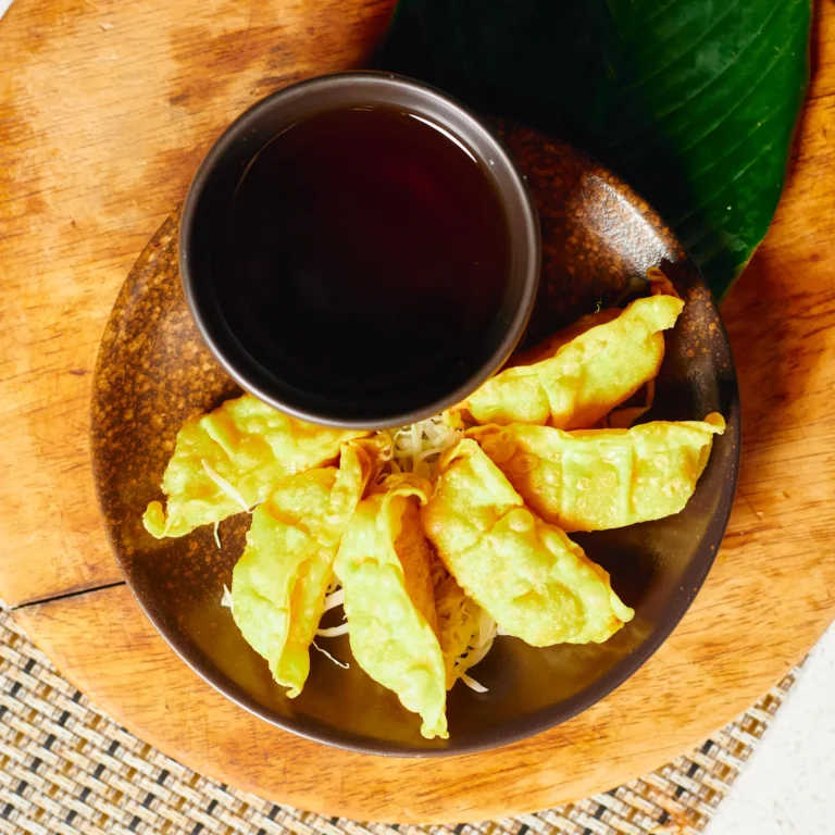 Pan fried chicken gyoza dumplings served with soy vinegar dipping sauce on a wooden plate