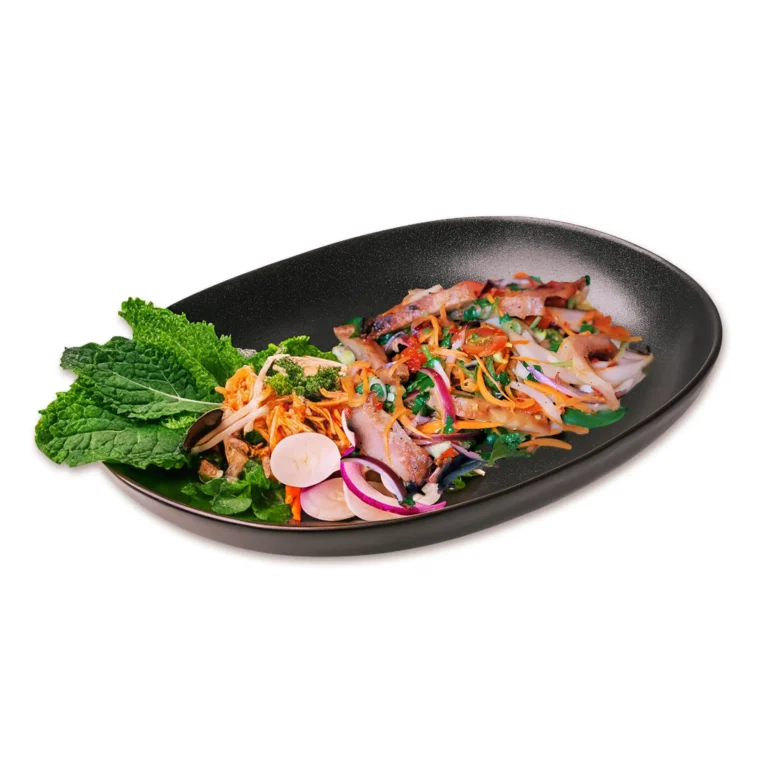 Thai grilled beef salad with mixed herbs, red onions, carrots, and mint on a black plate